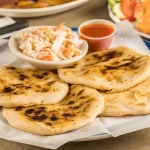 Keywords: pupusas, Salvadoran food, cheese pupusa, pupusas revueltas, masa harina recipe, Chef Ed, curtido slaw, salsa roja, Central American street food, grilled pupusa, gluten-free Latin food, Latin comfort food, pupusas de queso, pork pupusa, authentic pupusas, Loroco filling, homemade tortillas, Salvadoran cuisine, El Salvador recipes, Latin cheese dish, Latin American cuisine, fermented cabbage, healthy Latin meals, corn tortilla pupusa, stuffed masa dough, cheesy Latin snack, meat and cheese pupusa, pupusas tradition, Chef Ed pupusa recipe